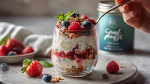 Greek yogurt parfait with strawberries, blueberries, granola, and honey in a clear glass.