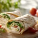 Turkey and cheese wrap with lettuce and tomato in a flour tortilla, sliced and ready to serve.