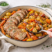 One-pan roasted pork tenderloin with carrots, potatoes, and onions, golden and caramelized in a skillet.