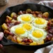 One-pan breakfast hash with potatoes, bacon, and sunny-side-up eggs cooked in a skillet.
