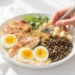 Budget protein sources: eggs, lentils, canned tuna, chicken, Greek yogurt on cutting board