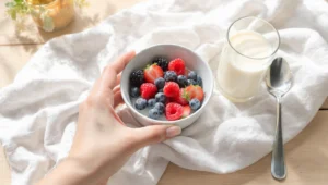 Healthy breakfast bowl with oatmeal, berries, nuts for weight loss on wooden table