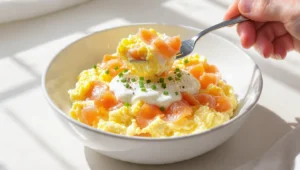 Quick healthy low-carb breakfast with eggs, avocado, smoked salmon, and fresh greens on a white plate.