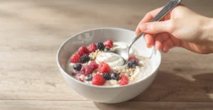 Quick healthy breakfast recipes for gut health with yogurt, berries, avocado toast, and lemon water on a white kitchen table.